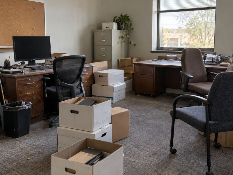 A vacated office with desks, chairs and boxes left in place