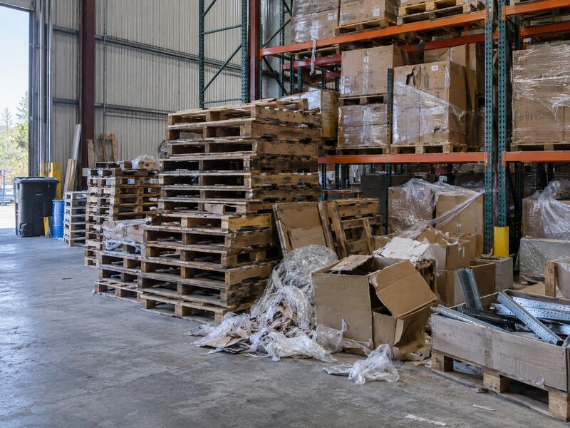 A warehouse with stacked pallets and discarded stock