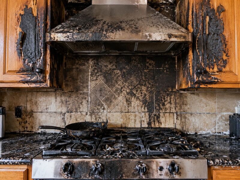 A stovetop and range hood blackened by fire