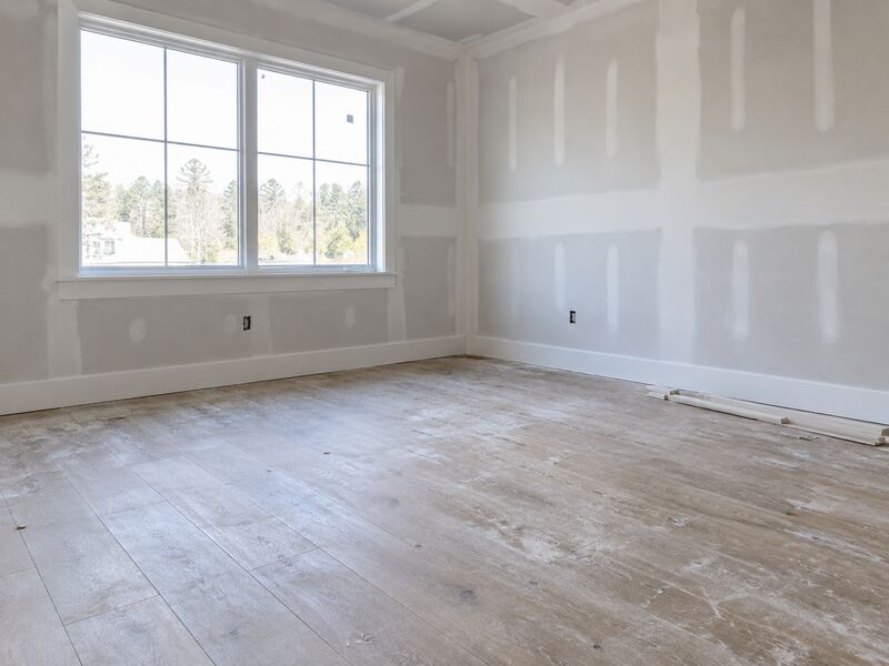 A newly built house interior with drywall up and dust on the floor