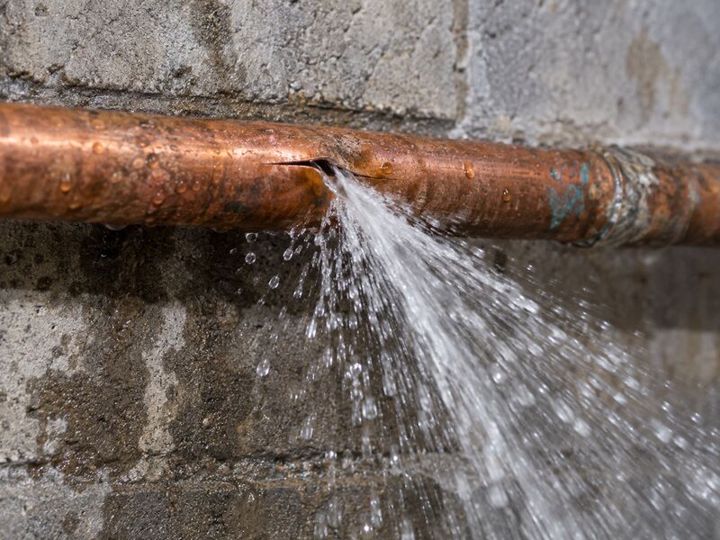 Water jetting from a split supply pipe against a basement wall